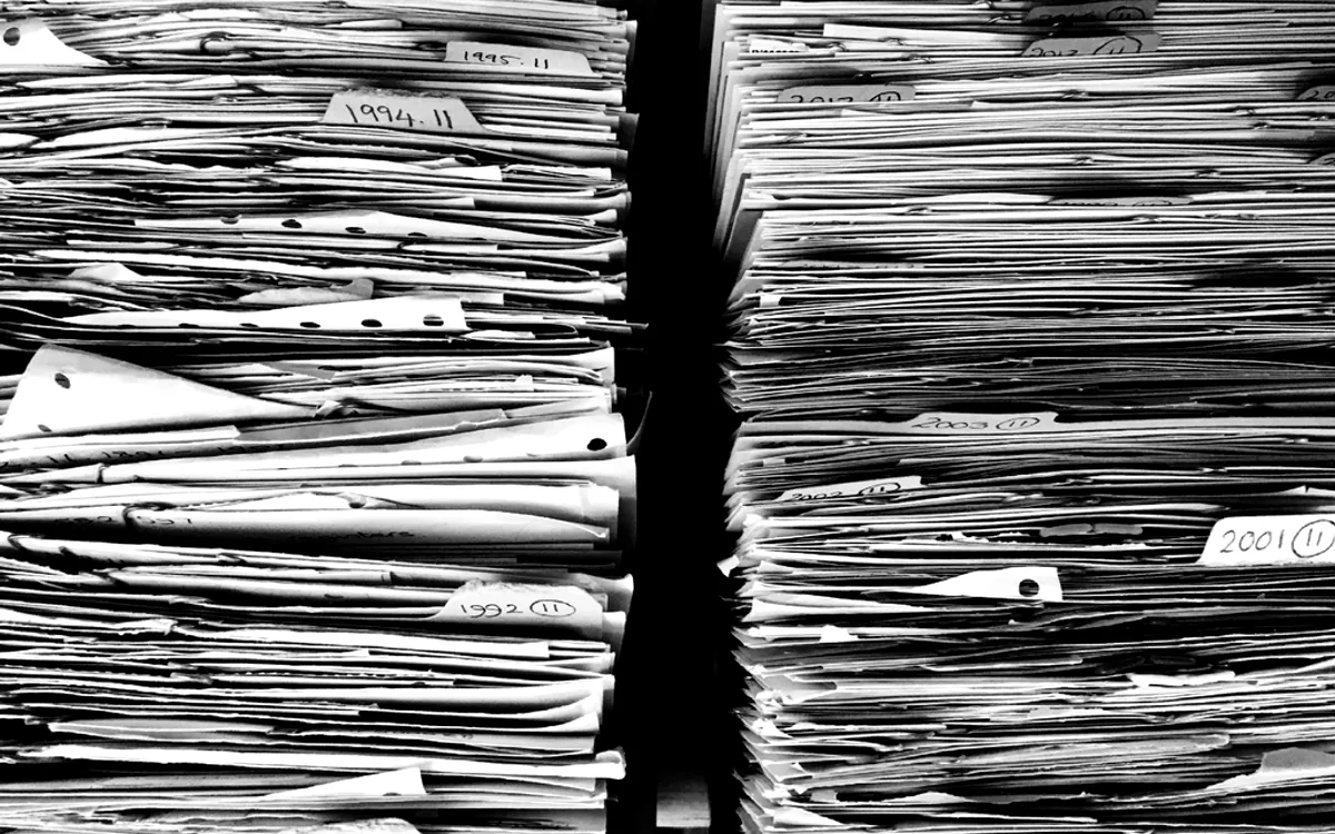 Rayonnages de documents ordonnés, évoquant un flux documentaire à traiter en volume