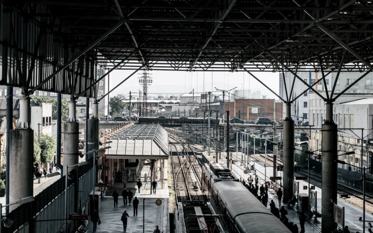 Quais et voies convergentes sous une halle ferroviaire, évoquant des flux de demandes canalisés vers les bons interlocuteurs