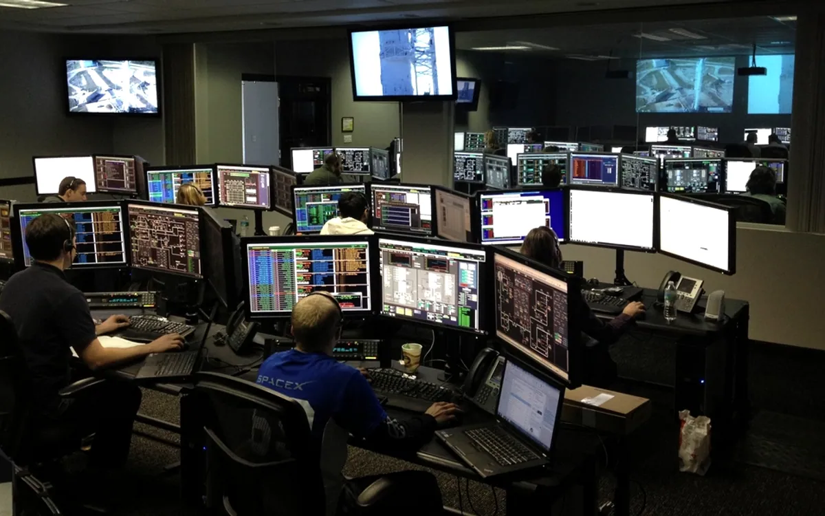 Une salle de contrôle où des opérateurs surveillent des écrans.