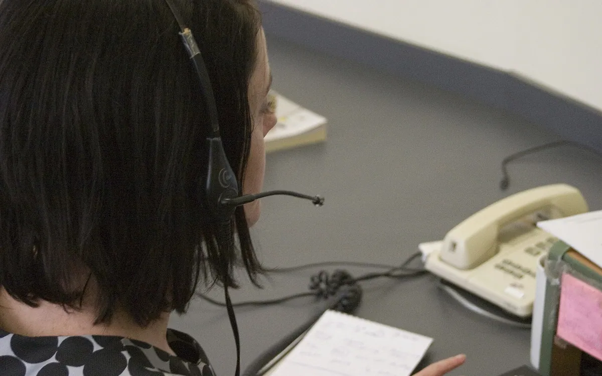 Une personne portant un casque téléphonique à un poste de travail.